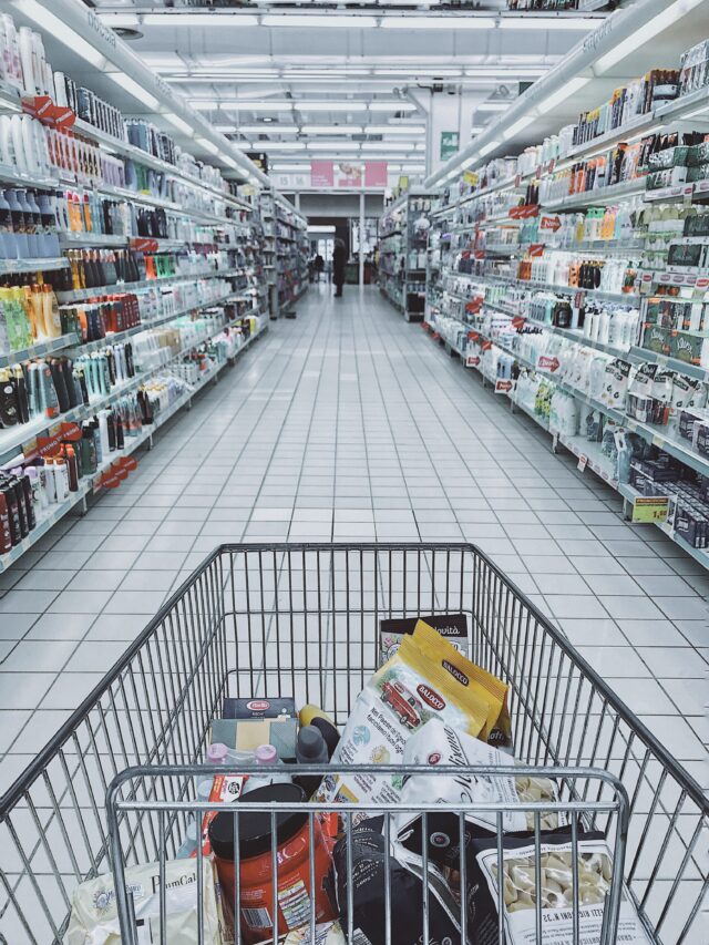 An aisle of a Pennsylvania supermarket filled with various personal care and household products on both sides. The image is taken from behind a shopping cart, which contains food items and household supplies, including pasta, sauce, and cleaning products. (This is before the unfortunate supermarket accident that eventually led to compensation.)