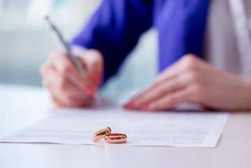 man signing papers with wedding rings